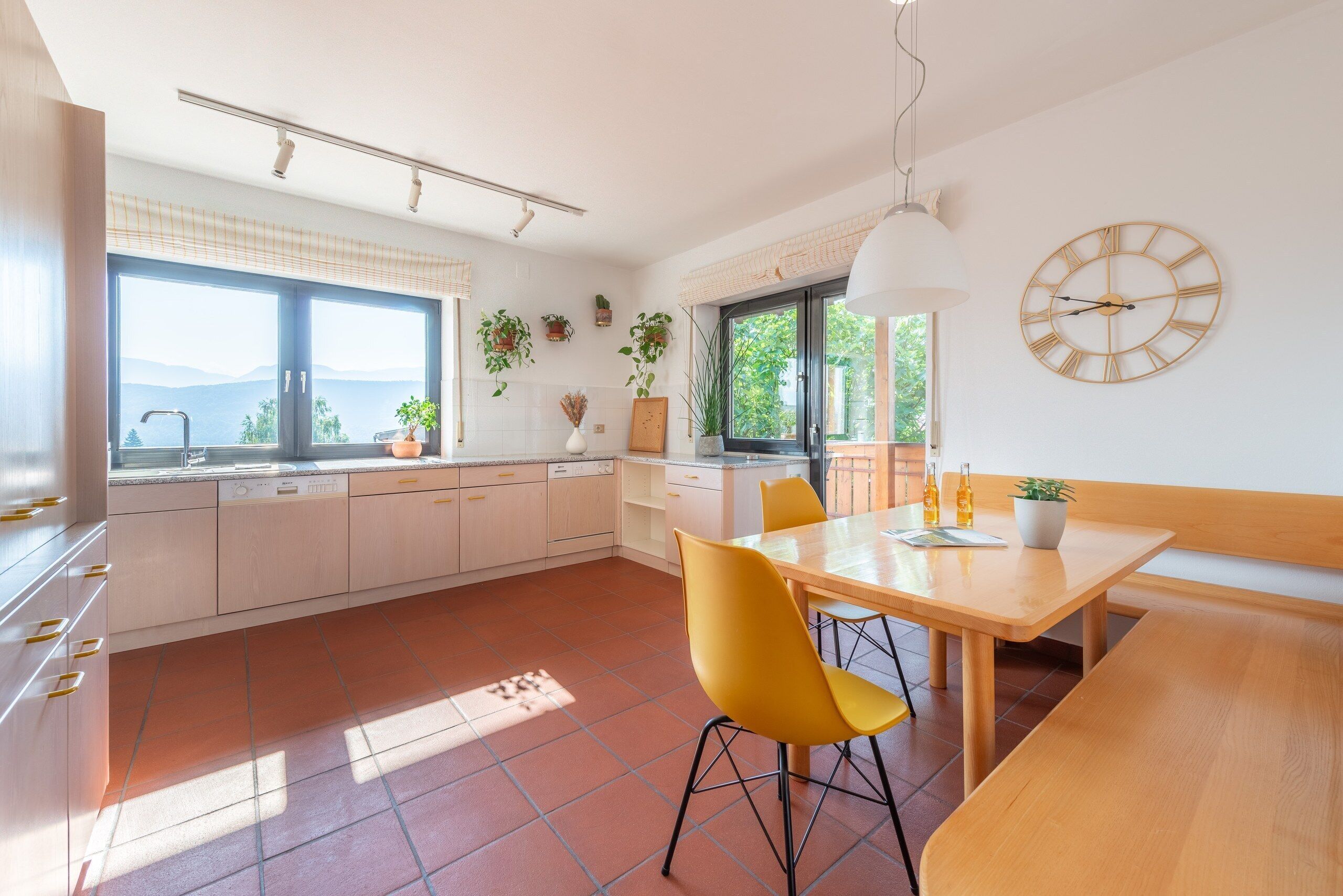 Une cuisine moderne avec un coin repas, de grandes fenêtres et une vue sur l’extérieur.