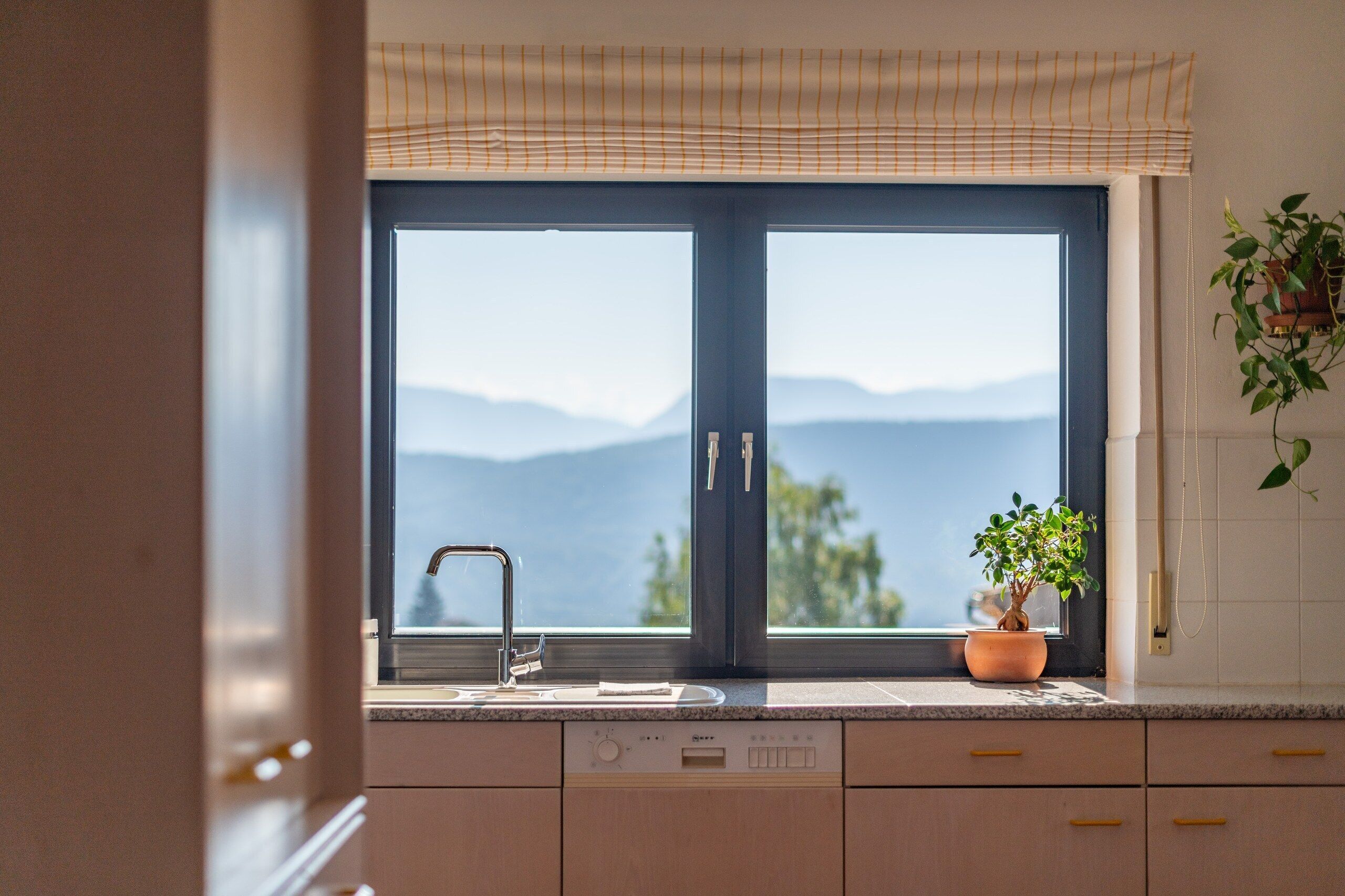 A kitchen with a large window, a sink, and a potted plant.