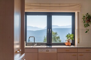 A kitchen with a large window, a sink, and a potted plant.
