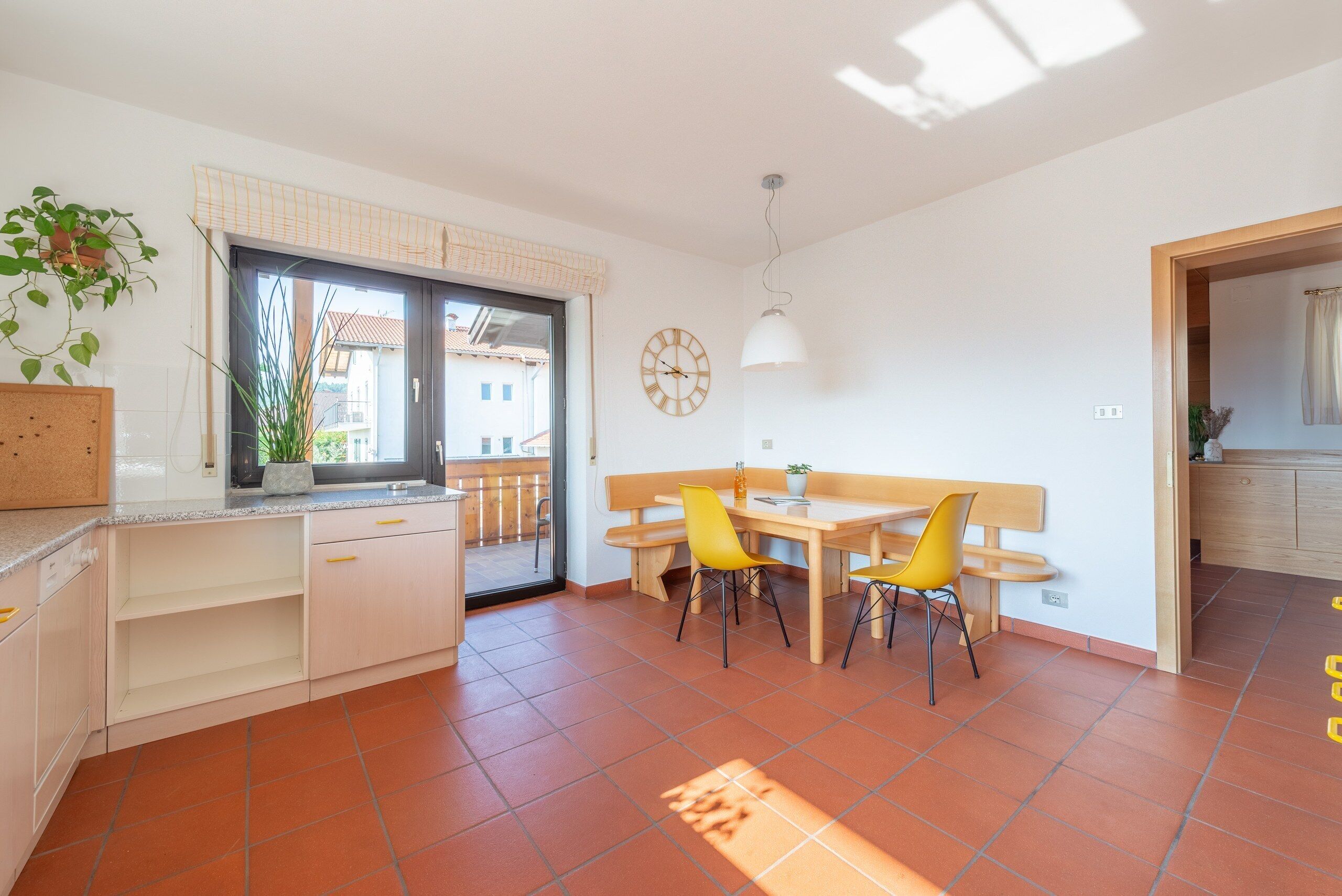 Una cocina moderna con comedor, un reloj y vistas al exterior.