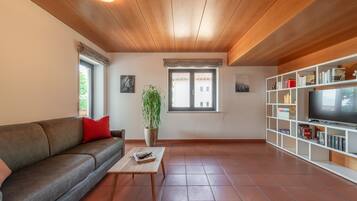 A living room with a sofa, a coffee table, a plant, a TV, and a bookshelf.