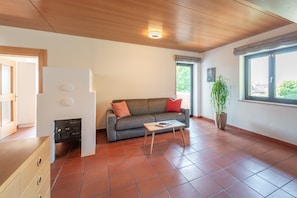 A living room with a sofa, a coffee table, a fireplace, and a large window.