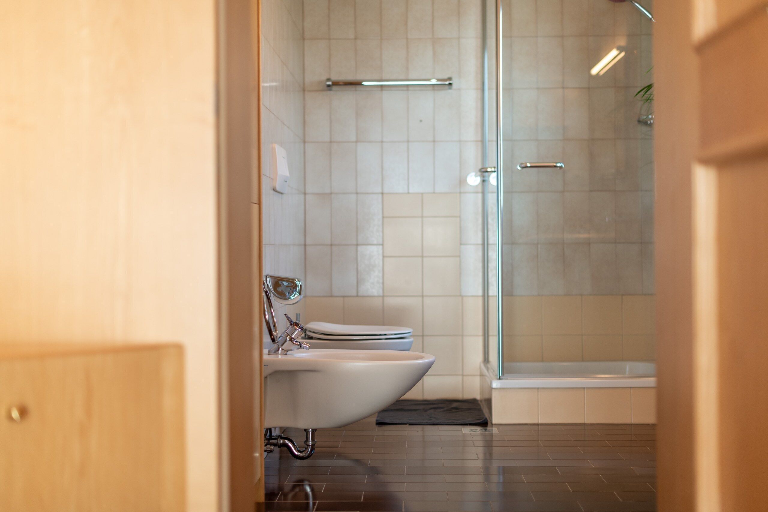 Une salle de bain moderne équipée de toilettes, d’un bidet et d’une douche à parois de verre.
