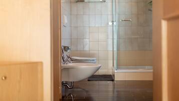 Une salle de bain moderne équipée de toilettes, d’un bidet et d’une douche à parois de verre.