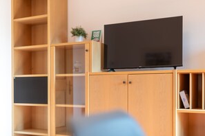 A wooden entertainment unit with a flat-screen TV on top, a small potted plant, and a box labeled 'FIAT'.