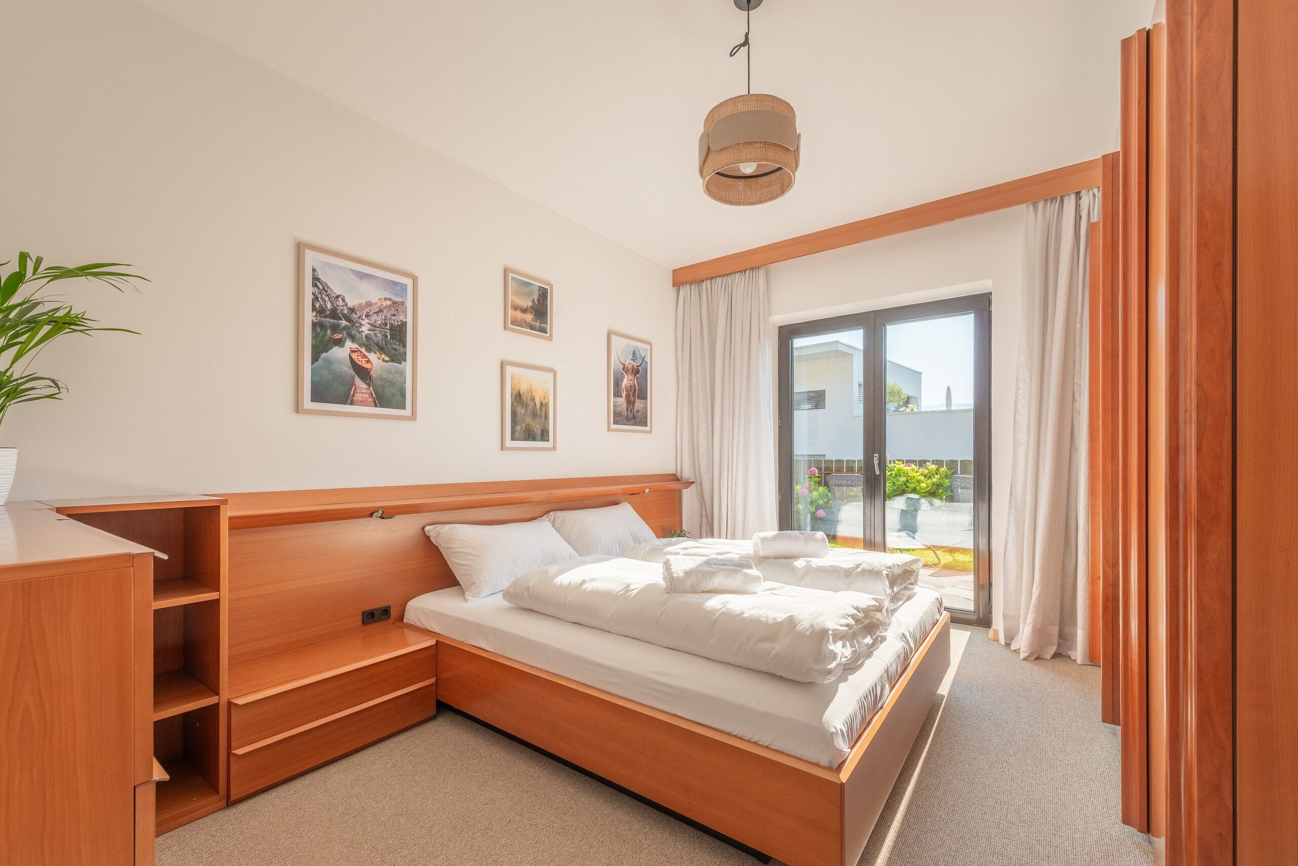 Un dormitorio con cama de madera, un escritorio y un gran ventanal con cortinas.