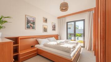 Un dormitorio con cama de madera, un escritorio y un gran ventanal con cortinas.