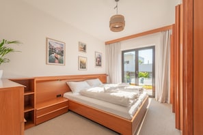 Un dormitorio con cama de madera, un escritorio y un gran ventanal con cortinas.