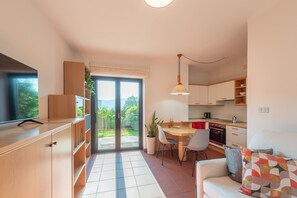 A modern kitchen with a dining area, a sofa, and a view of the outdoors. - 714A Apartment Villa Vardia (Caldaro sulla strada del vino)