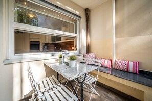 Una cocina compacta con electrodomésticos modernos, un comedor con mesa de mármol y una sala de estar con cojines estampados.