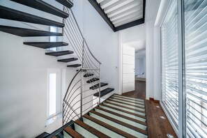 A modern staircase with glass railings and wooden steps.