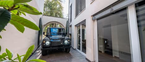 Un vehículo negro estacionado en un camino de acceso estrecho, entre edificios.
