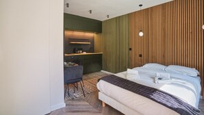 A modern hotel room with a bed, a desk, and a kitchenette. - Superb New Studio in Neuilly Porte Maillot (Neuilly-sur-Seine)