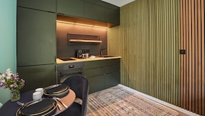 A compact kitchen with dark green cabinetry, a built-in oven, and a coffee machine. - Superb New Studio in Neuilly Porte Maillot (Neuilly-sur-Seine)