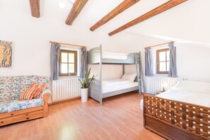 Une pièce avec un lit superposé, un canapé, un radiateur et une plante.