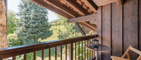 Ein Holzbalkon mit Blick auf einen Garten und Bäume.
