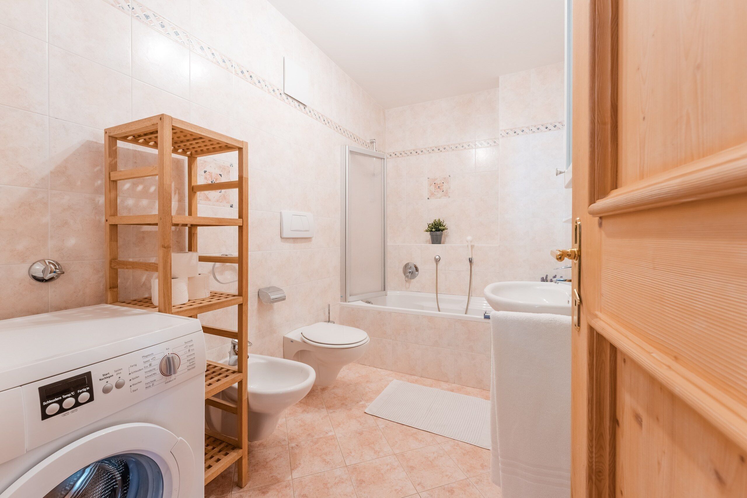 Une salle de bain moderne équipée d’un lave-linge, de toilettes et d’une baignoire.