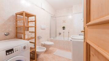 Une salle de bain moderne équipée d’un lave-linge, de toilettes et d’une baignoire.