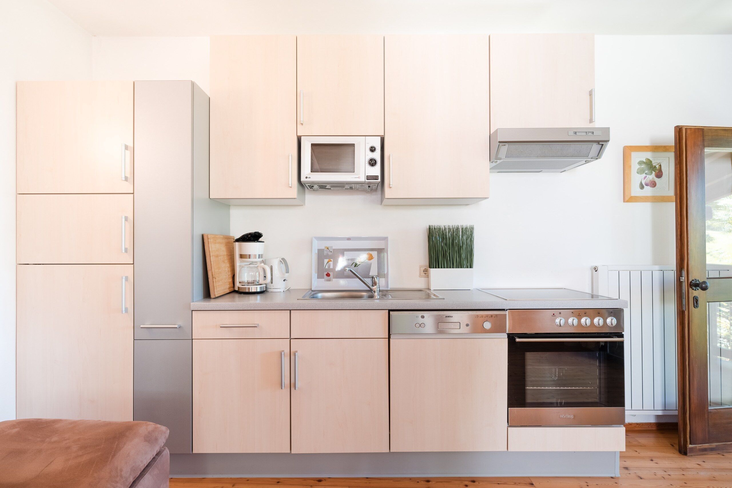 A compact kitchen with a microwave, coffee maker, sink, and oven.