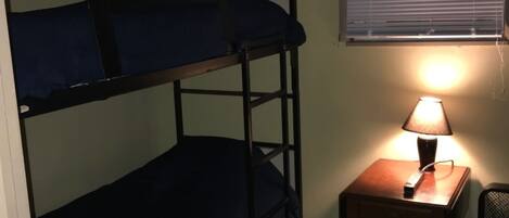 A bunk bed with a desk and lamp, a window with blinds, and a "Smoking Prohibited" sign.