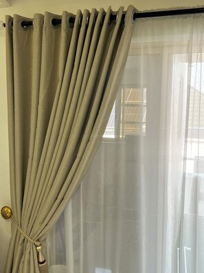 Una habitación con una ventana cubierta por una cortina color beige atada en la parte superior.