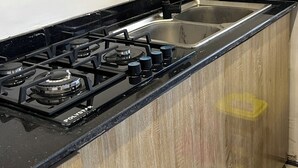 A kitchen with a black stove, stainless steel sink, and wooden cabinets.