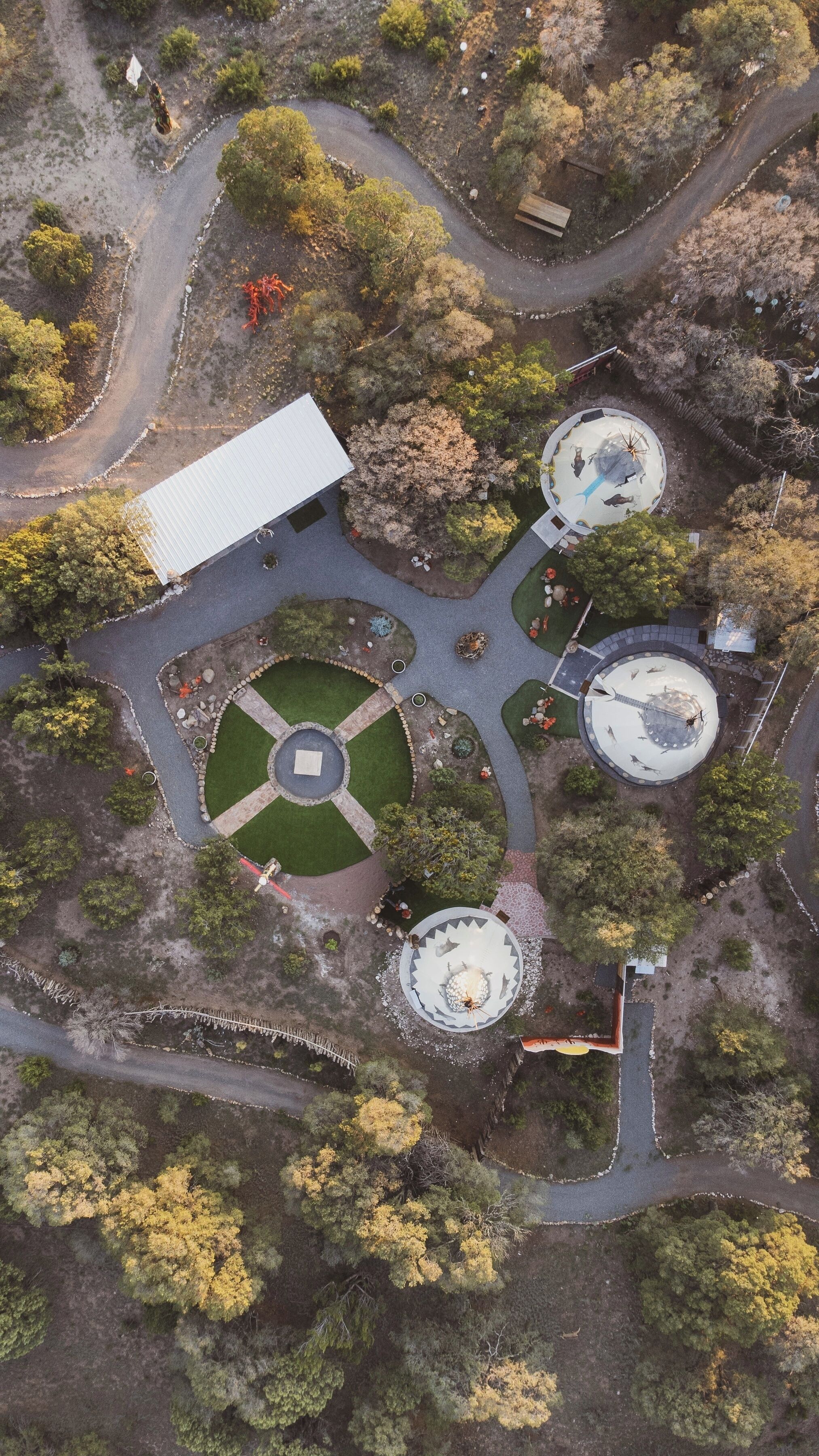 Vista aérea de un área ajardinada con senderos, un jardín circular central y tres estructuras circulares.