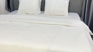 A neatly made bed with a grey headboard and white bedding. - Serene environment perfect for a pri8 short or long stay.Beach,bar n mall nearby (Eti-Osa)
