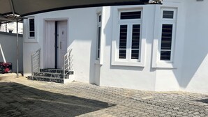 A building with a white exterior, a covered outdoor area with hexagonal paving, and a staircase leading to a door. - Serene environment perfect for a pri8 short or long stay.Beach,bar n mall nearby (Eti-Osa)