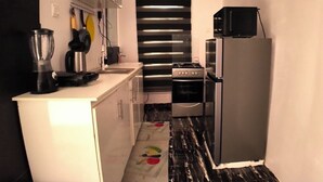 A compact kitchen with a stove, refrigerator, and microwave. - Serene environment perfect for a pri8 short or long stay.Beach,bar n mall nearby (Eti-Osa)
