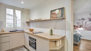 A modern kitchen with a wooden countertop, built-in oven, and a window. - Modern Apartment - Eiffel Tower Trocadero Place (Paris)