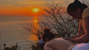 A sunset view from a balcony overlooking a body of water, with a person sitting and another standing nearby. - UNIQUE BEACH HOUSE CASA DI LUCA WITH STUNNING VIEW (Puerto Ángel)