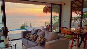 A modern living room with a large sliding glass door leading to a balcony overlooking the sea. - UNIQUE BEACH HOUSE CASA DI LUCA WITH STUNNING VIEW (Puerto Ángel)