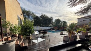 A wooden deck with outdoor seating, a pool, and potted plants. - Quiet house near Montpellier in a village on the edge of a forest (Teyran)