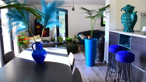A modern living room with a dining table, blue bar stools, a large blue vase, and a green decorative pot. - Quiet house near Montpellier in a village on the edge of a forest (Teyran)