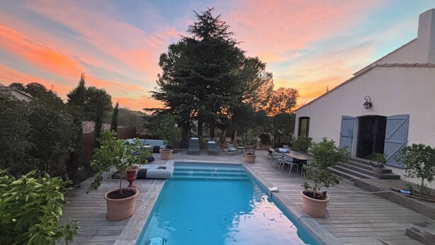 A swimming pool with a wooden deck, surrounded by potted plants and outdoor furniture. - Quiet house near Montpellier in a village on the edge of a forest (Teyran)