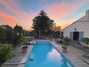 A swimming pool with a wooden deck, surrounded by potted plants and outdoor furniture. - Quiet house near Montpellier in a village on the edge of a forest (Teyran)