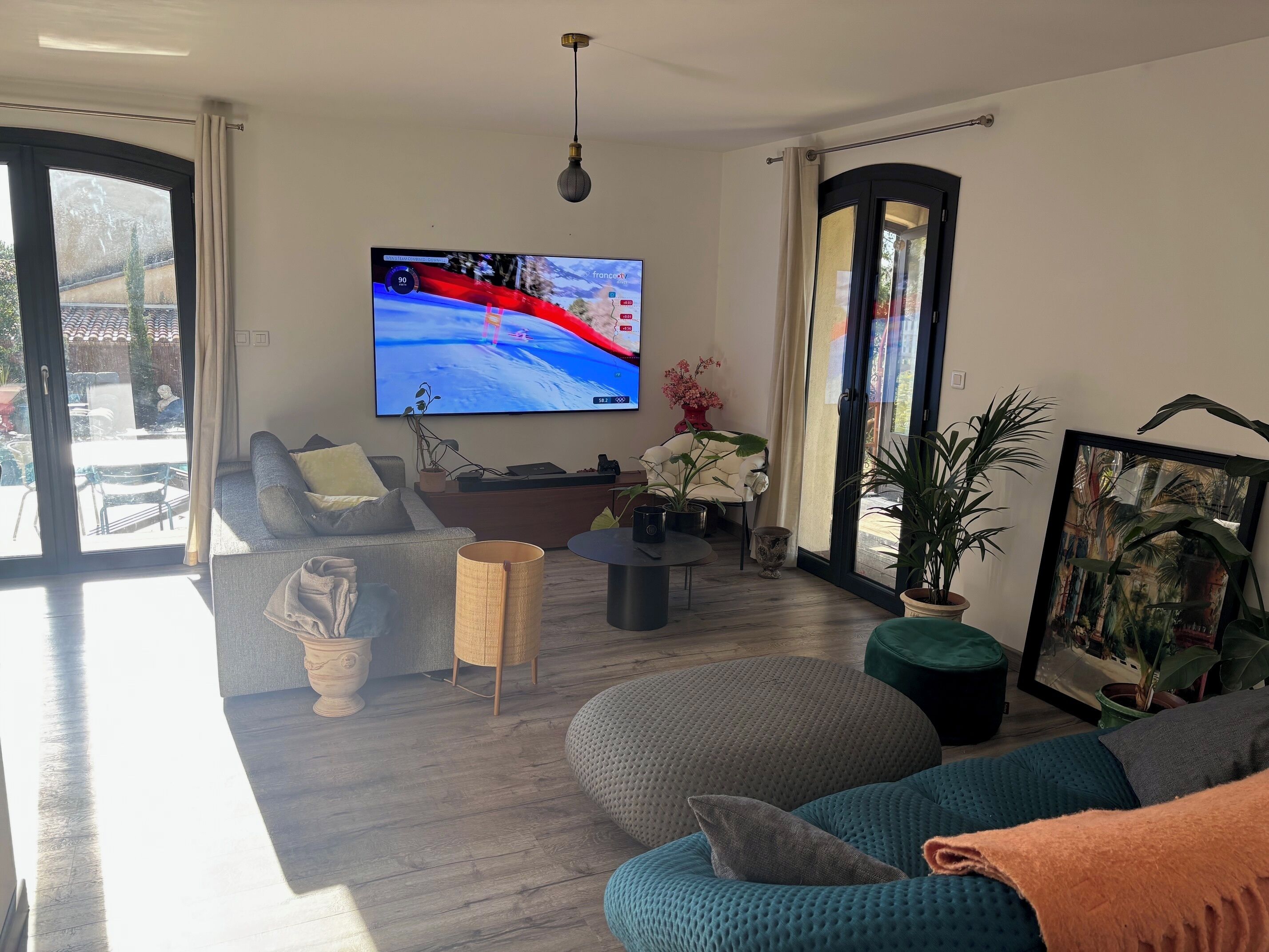 Una sala de estar moderna con un televisor grande, un sofá, una mesa de centro y un ventanal corredero que da a un espacio exterior.