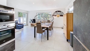 A modern kitchen with a dining area, featuring a large oven, a dining table with chairs, and a view of the outdoors through large windows. - Modern house for 4 people close to Cavalière beach in Le Lavandou (Le Lavandou)