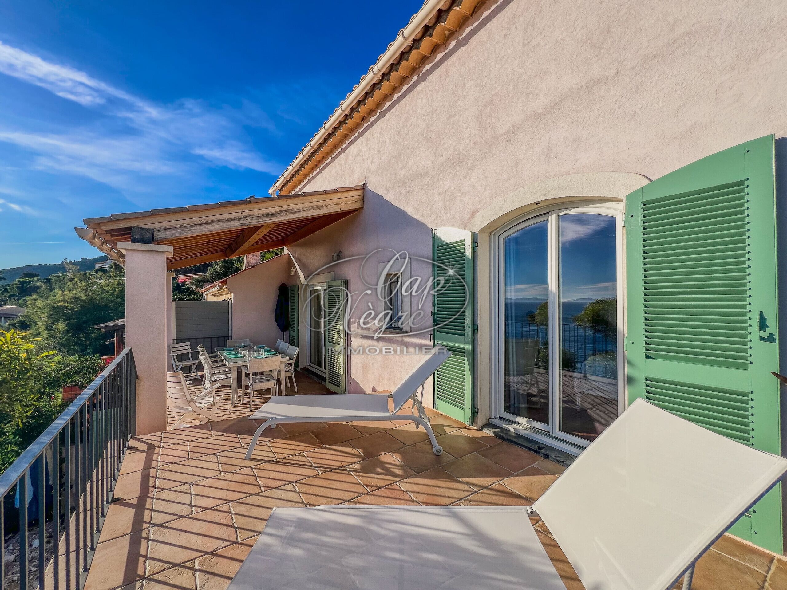 A terrace with a table and chairs, a pergola, and a view of the surrounding landscape.