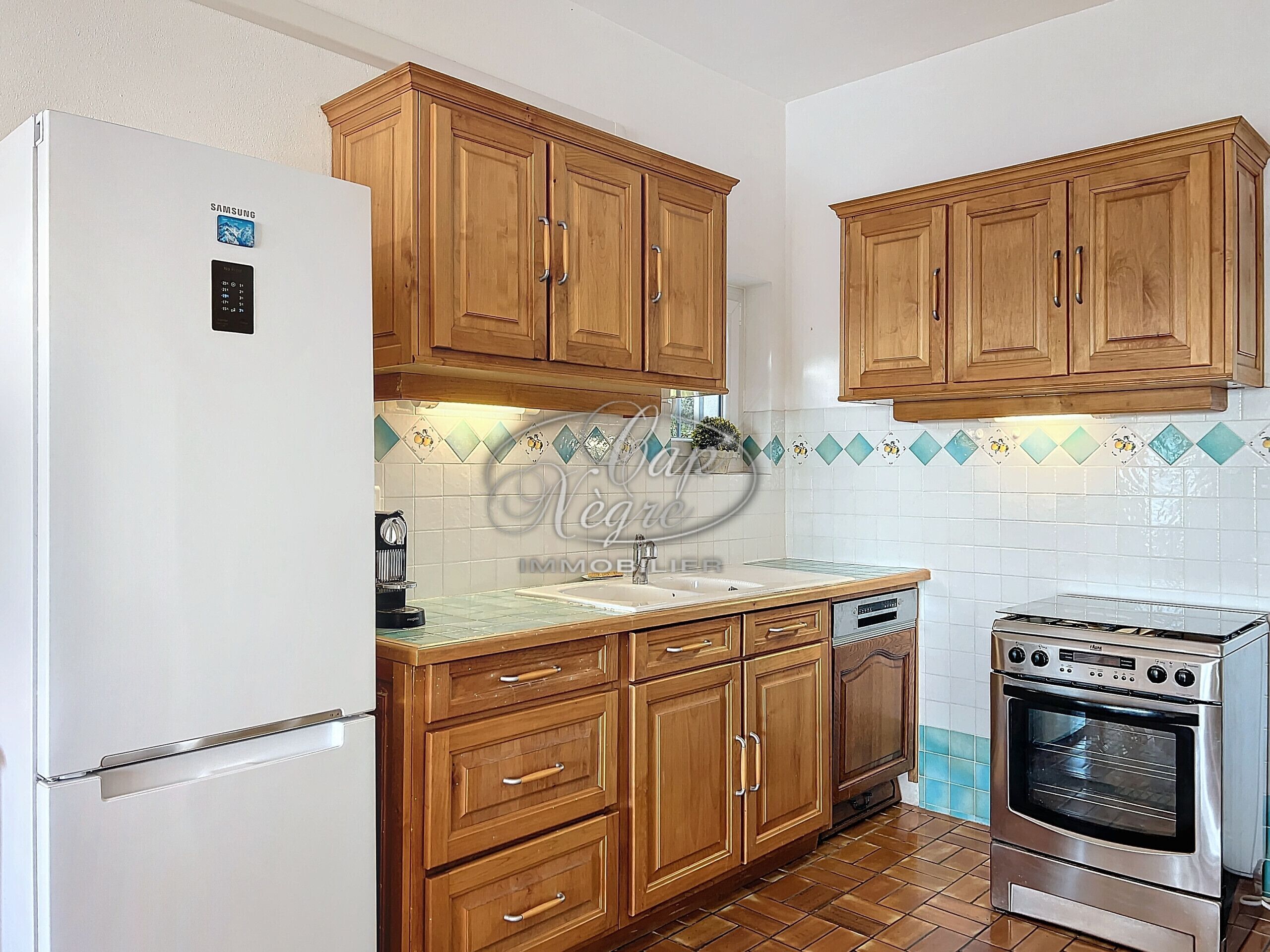 A kitchen with wooden cabinets, a white refrigerator, a sink, and a stove.