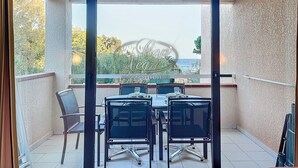 A balcony with a table and chairs, a view of the sea, and a textured wall.