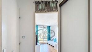 A doorway leading to a bedroom with a bed, curtains, and a small rug. - Apartment for 4 people in Le Canadel (Rayol-Canadel-sur-Mer)