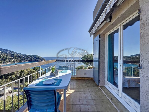 A balcony with a table and chairs, a view of the sea, and a mountainous landscape. - Apartment for 4 people in Le Canadel (Rayol-Canadel-sur-Mer)