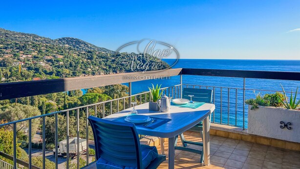 A balcony with a table and chair, overlooking a coastal view with a clear sky. - Apartment for 4 people in Le Canadel (Rayol-Canadel-sur-Mer)
