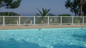 A clear blue pool with a white fence and palm trees in the background. - Apartment for 4 people in Le Canadel (Rayol-Canadel-sur-Mer)