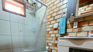 Un baño con inodoro, ducha, lavabo y espejo.