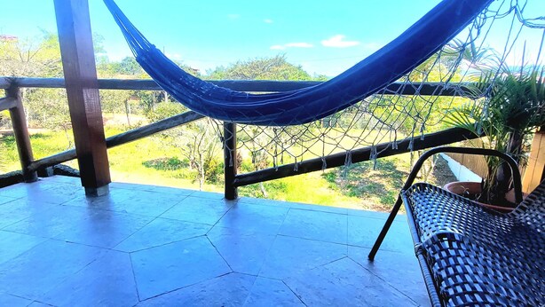 Una hamaca bajo una estructura de madera con vistas a follaje.