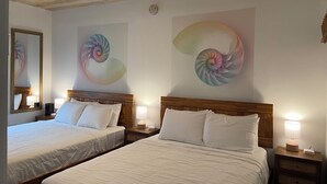 A hotel room with two beds, wooden headboards, bedside tables with lamps, and a ceiling with exposed beams.