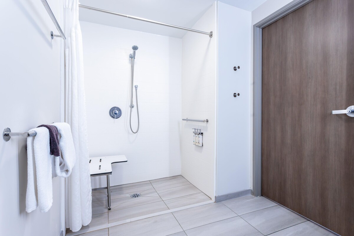 Um banheiro moderno com chuveiro, vaso sanitário e porta-toalhas.